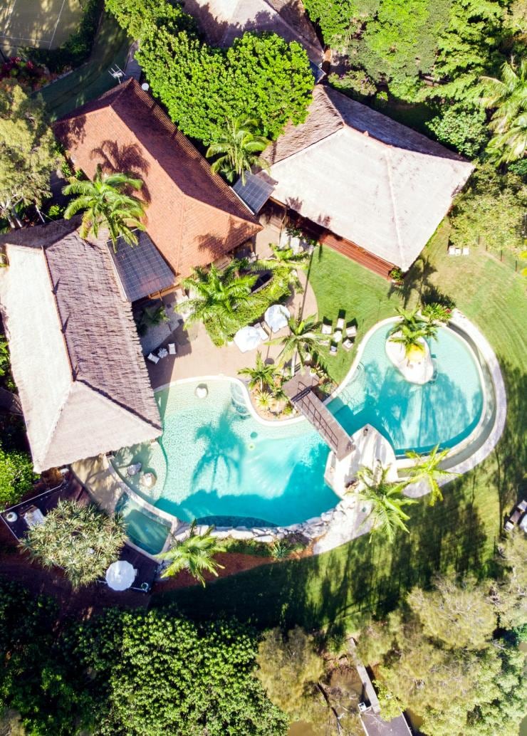 Vue aérienne d'une piscine entourée d'arbres et de villas près du littoral à Makepeace Island, Noosa, Queensland © Makepeace Island