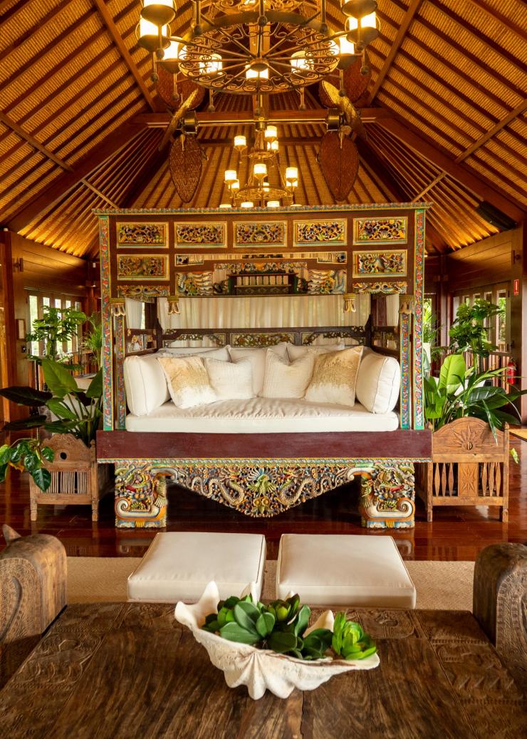 L'intérieur d'une villa en bois dotée de meubles sculptés et d'une grande méridienne au centre de la pièce à Makepeace Island, Noosa, Queensland © Makepeace Island