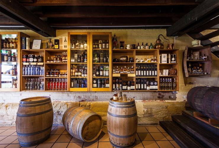 Numerose bottiglie di distillati esposte in una sala con scaffali in legno e botti alla Lark Distillery, Hobart, Tasmania © Tourism Tasmania/Nick Osborne