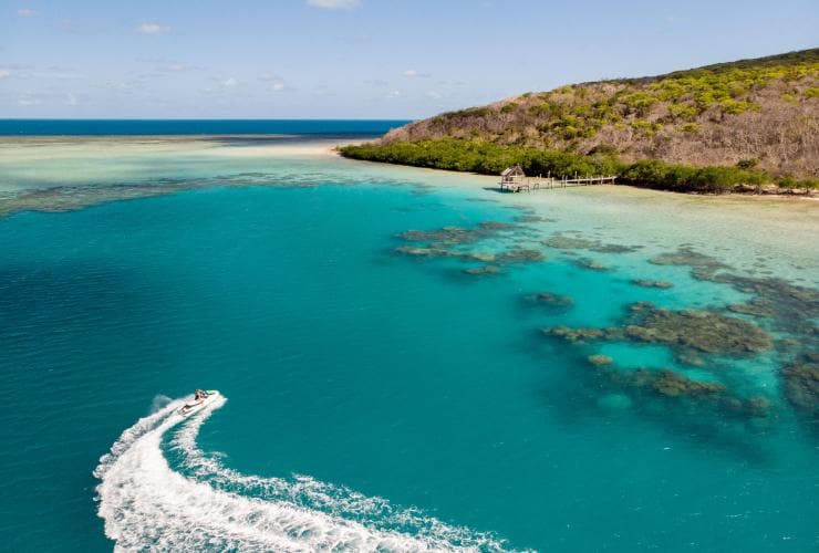 Vista aerea di una moto d'acqua che lascia dietro di sé una scia bianca nei pressi di Haggerstone Island, Grande Barriera Corallina, Queensland © Tourism and Events Queensland
