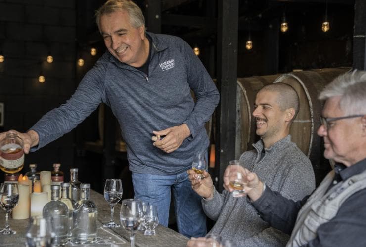 塔斯曼尼亞塔斯曼半島的McHenry Distillery釀酒廠職員正為面露笑容安坐桌旁的客人奉上美酒©澳洲旅遊局