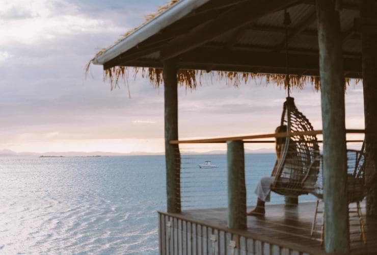 昆士蘭州南大堡礁南瓜島生態度假村內一女子坐在椅上遠眺海洋©南瓜島生態度假村